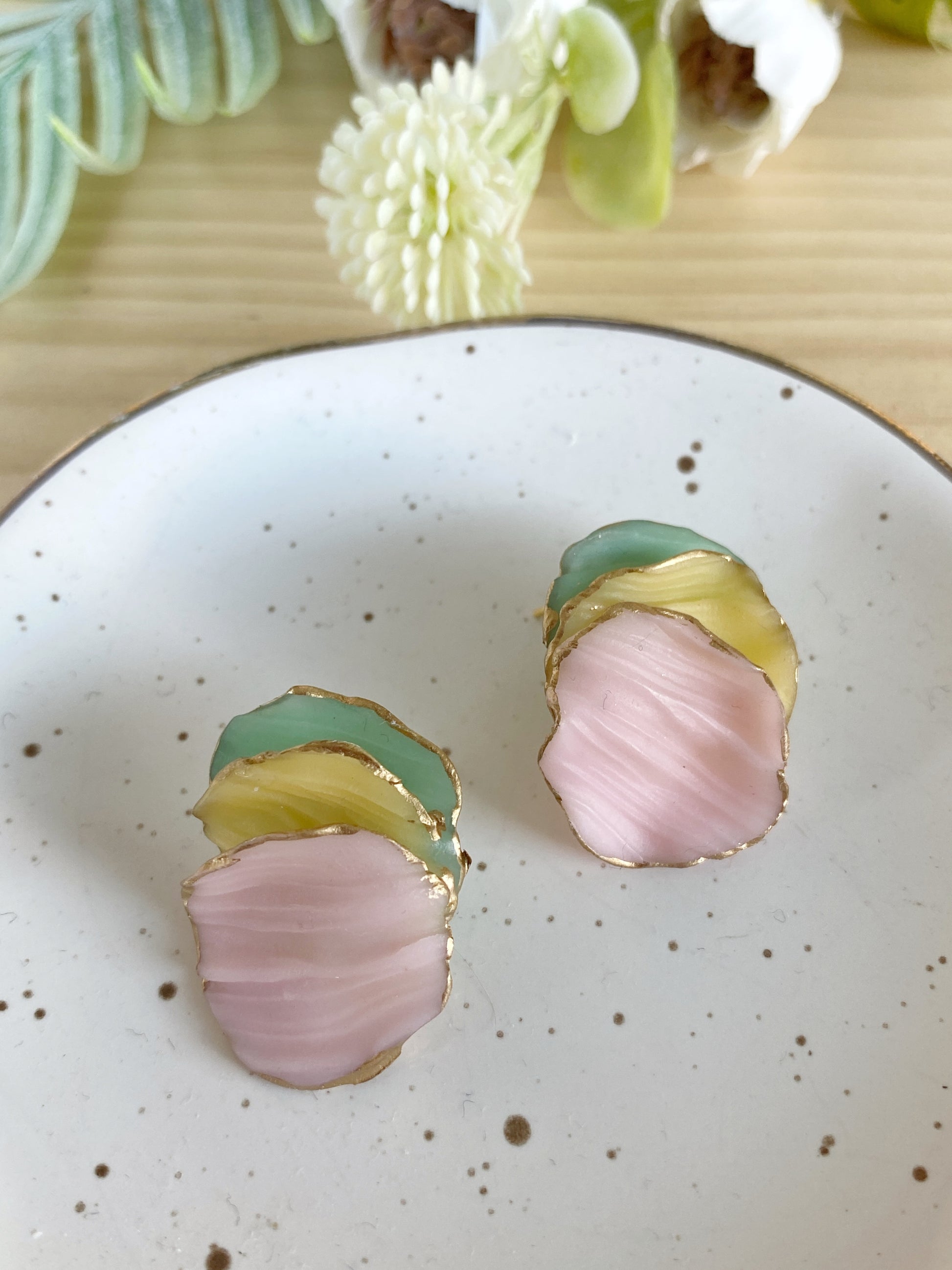 Pendientes de arcilla polimérica de la colección Pétalos en tonos rosa, amarillo y verde menta, con formas orgánicas superpuestas y bordes dorados.