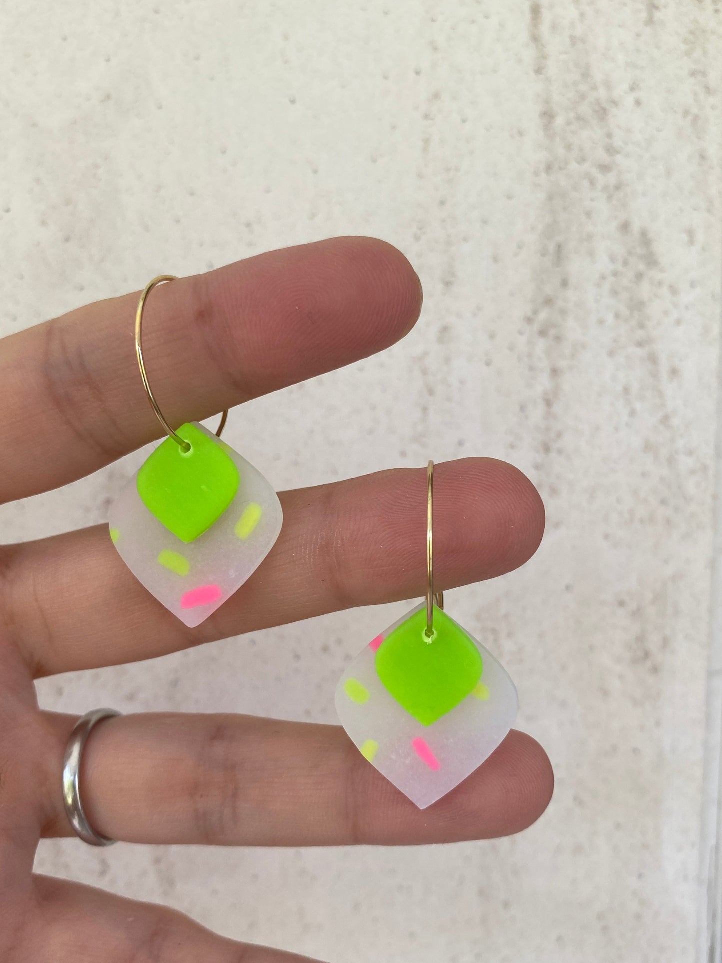 Pendientes geométricos de arcilla polimérica rombos sprinkles neón verde  sobre mano